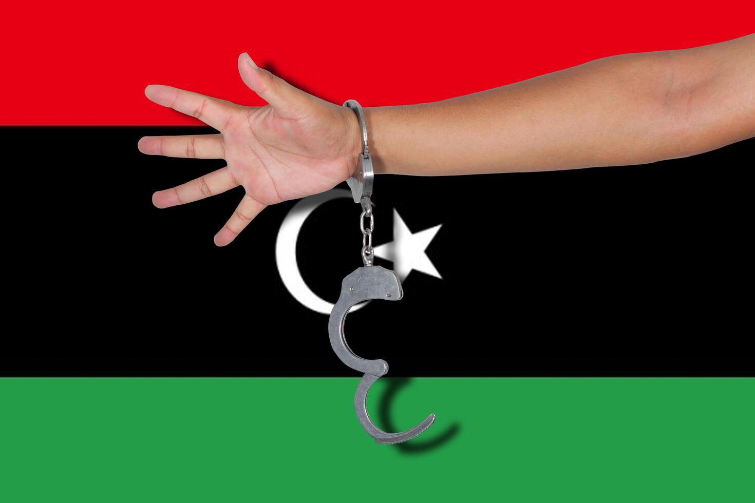 Handschellen mit Hand auf Libyen-Flagge foto