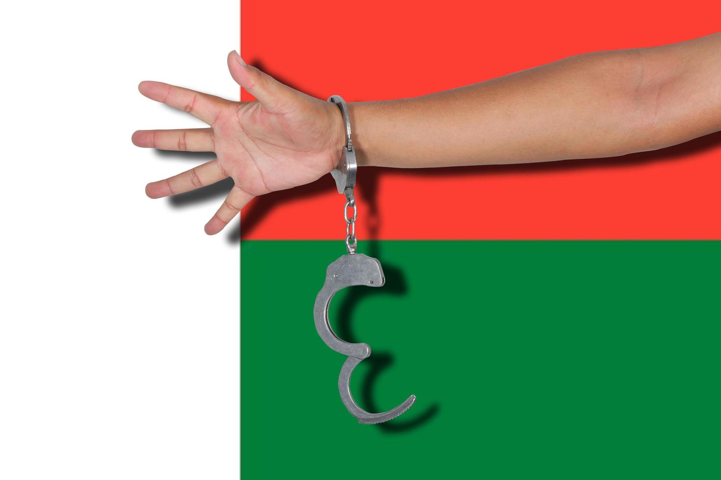 Handschellen mit Hand auf Madagaskar-Flagge foto
