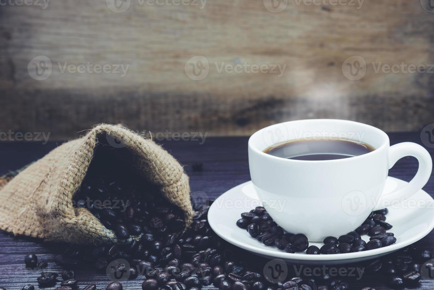 Seitenansicht der Kaffeetasse mit Rauch- und Kaffeebohnentisch foto