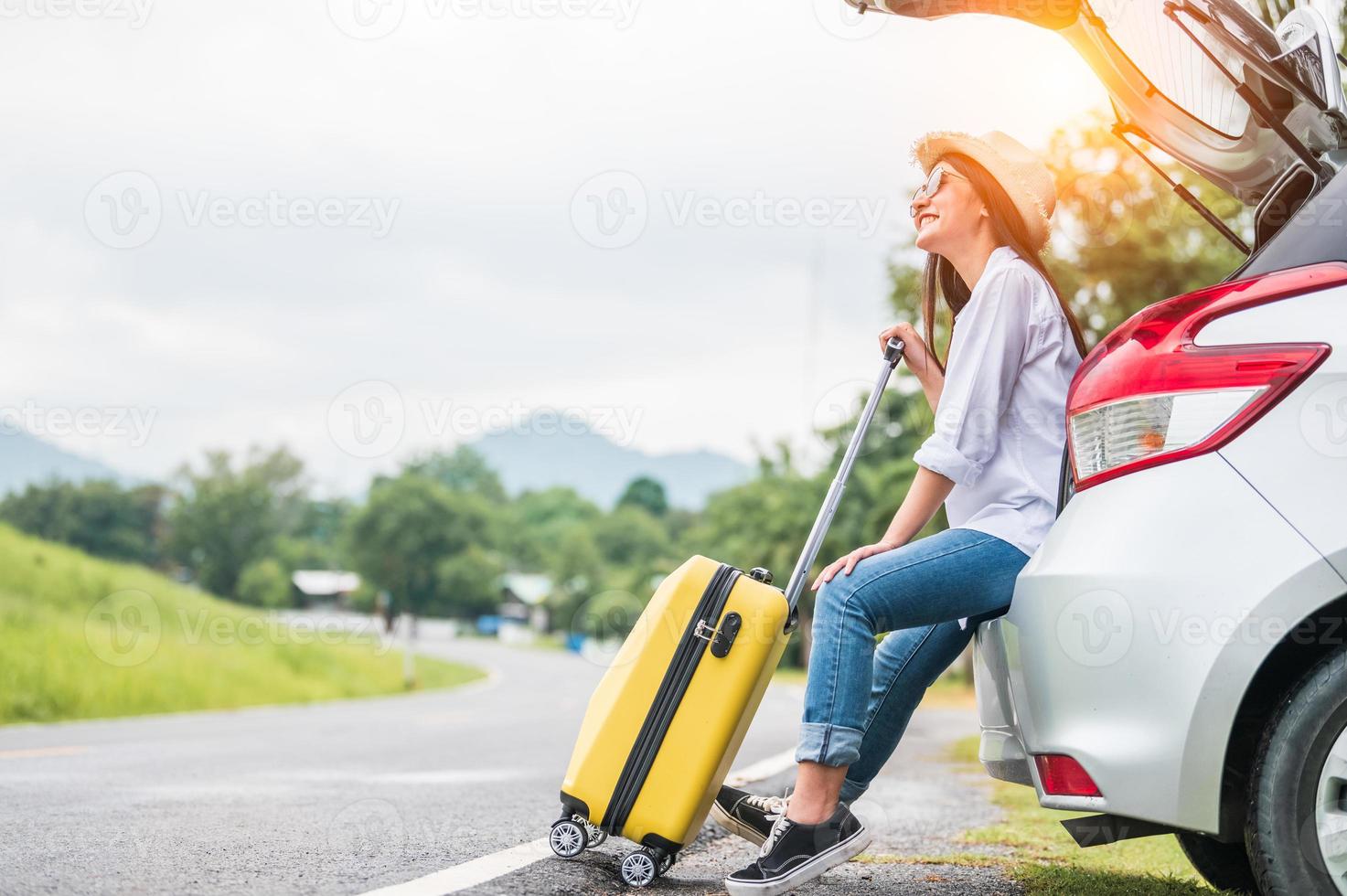 asiatische Frau, die ein Wochenende im Roadtrip mit gelbem Gepäck verbringt foto