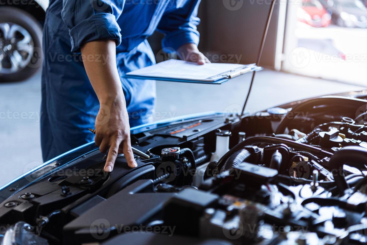 Automechaniker hält Zwischenablage und überprüft das Wartungsfahrzeug foto