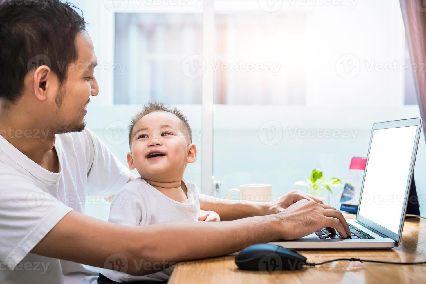 alleinerziehender Vater und Sohn, die glücklich zusammen Laptop benutzen foto