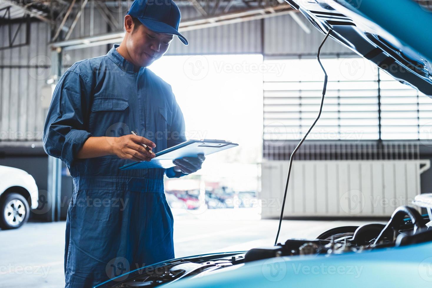 Automechaniker hält Zwischenablage und überprüft das Wartungsfahrzeug foto