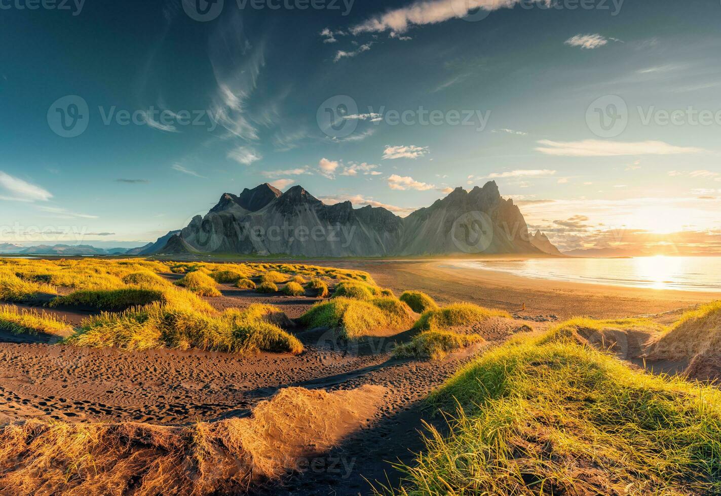 Sonnenaufgang leuchtenden Über Vestrahorn Berg mit Büschel von Gras auf schwarz Sand Strand im Sommer- beim Island foto