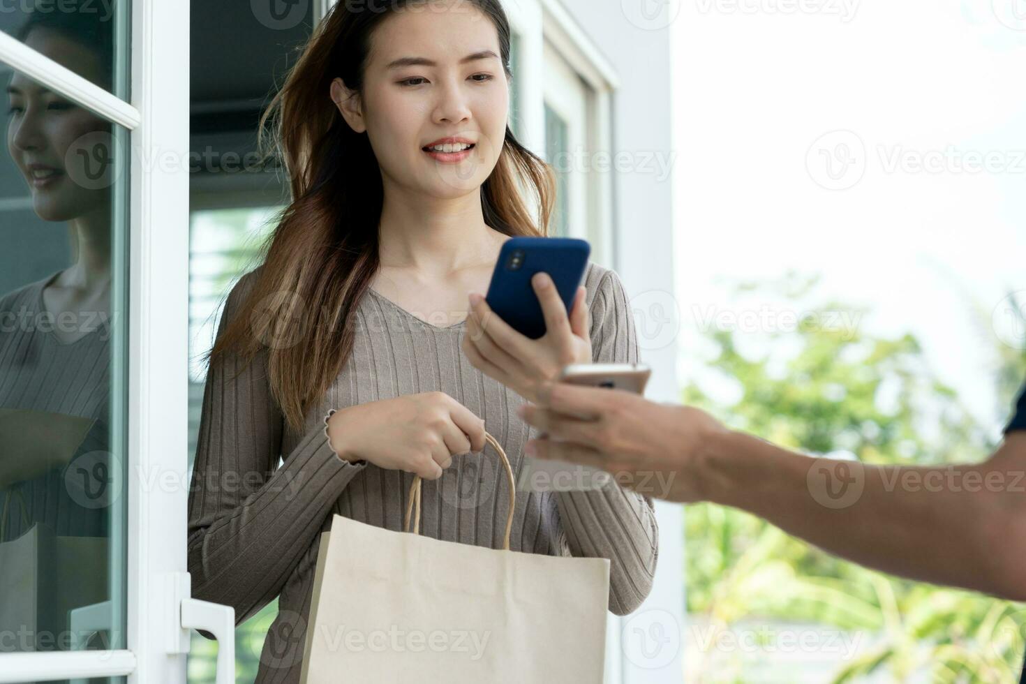 asiatische Frau mit glücklichem Lächeln scannt den QR-Code für die Bezahlung des Essens. lieferbote senden liefern express. Online-Shop, Papierbehälter, Imbiss, Postbote, Lieferservice, Pakete, elektronisches Geld, digitale Überweisung foto