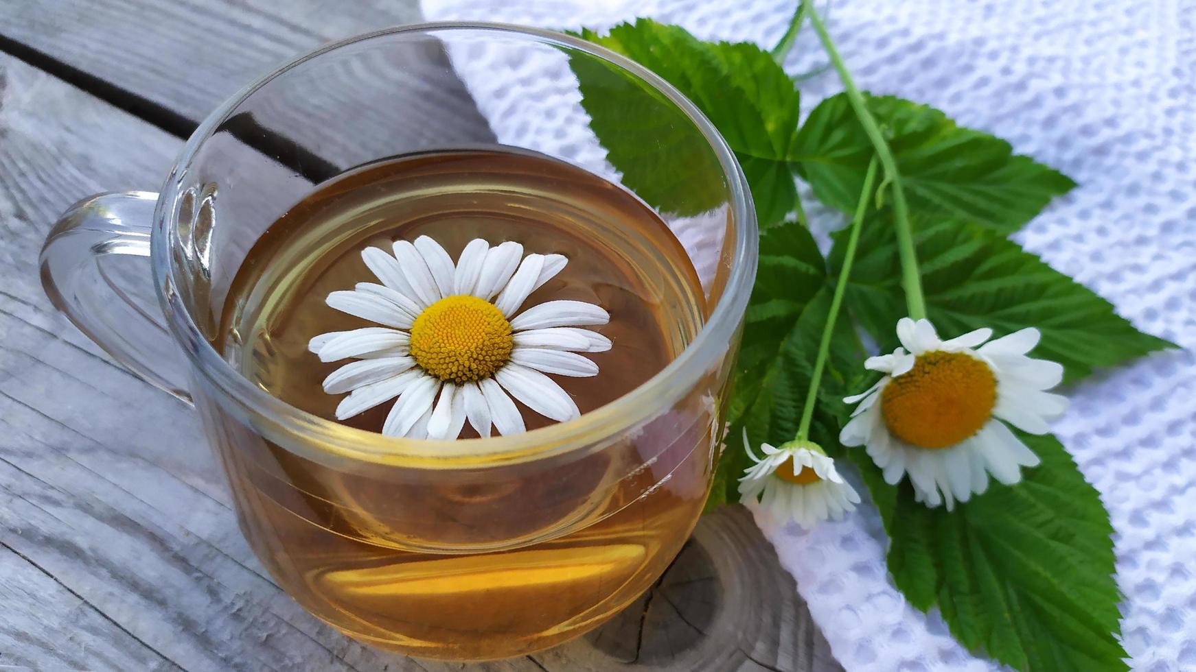 Kamillentee und Blumen. Tasse mit Tee auf Holzuntergrund foto