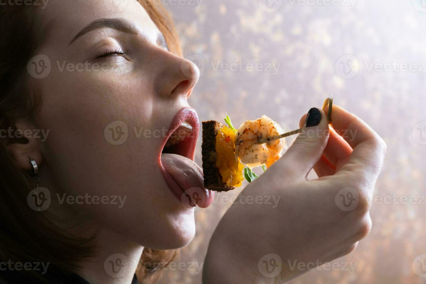Garnele und Mango Chutney Häppchen im weiblich Finger in der Nähe von öffnen Mund. Mini Sandwich Essen foto