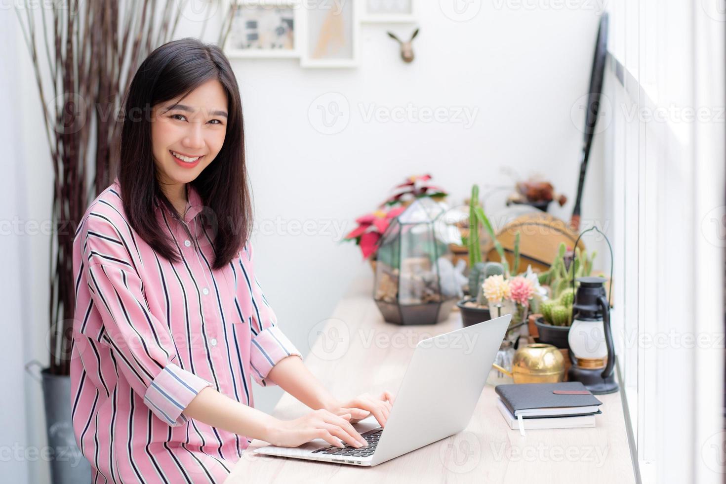 Porträt der jungen asiatischen Frau, die online am Laptop arbeitet. foto