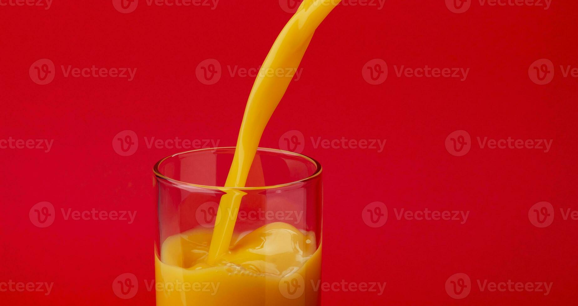 Orange Saft Gießen in Glas, isoliert auf rot Hintergrund foto