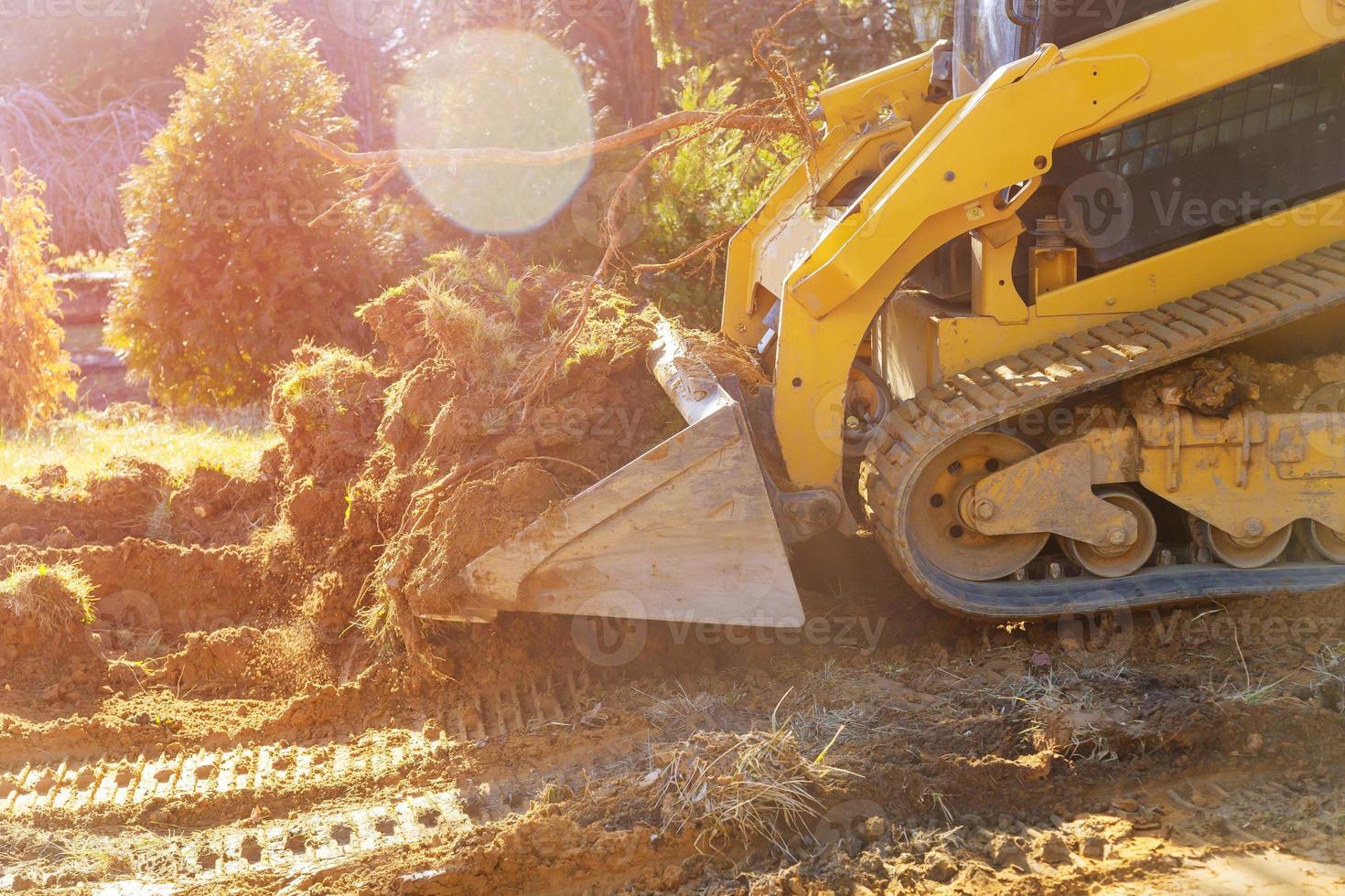 Mini-Bulldozer mit Erde bei Landschaftsbauarbeiten foto