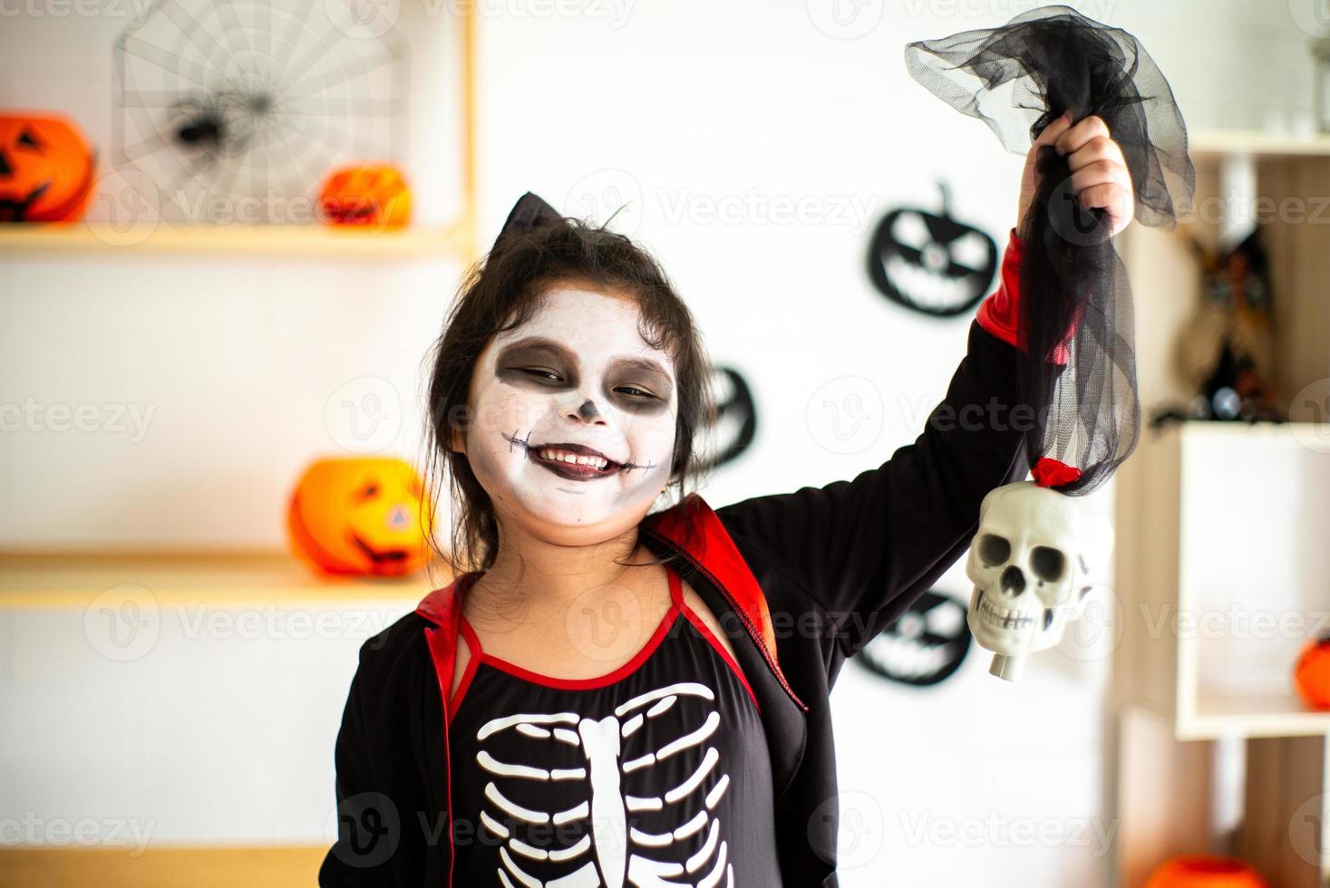 Porträt asiatisches kleines Mädchen im Halloween-Kostüm, das den Schädel hält foto