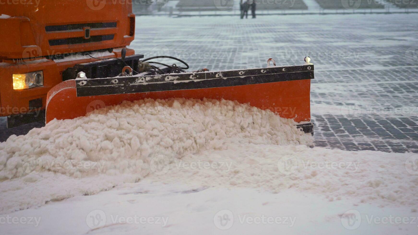 das Traktor reinigt das Pflaster im Winter. Traktor Reinigung das Straße von das Schnee. Bagger reinigt das Straßen von groß Beträge von Schnee im Stadt. ein Eimer Nahansicht reinigt das Bürgersteig von Schnee. foto