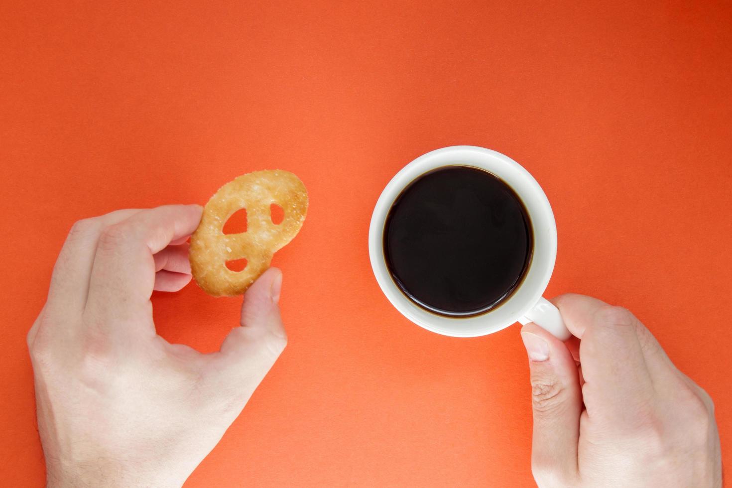 männliche Hände halten eine Tasse heißen Americano-Kaffee und Kekse auf einem hellen foto