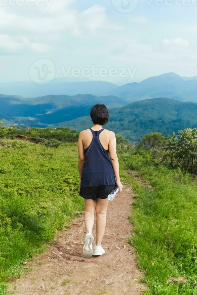 Frau Übung Gehen auf Hang Weg mit Berg Sicht. foto