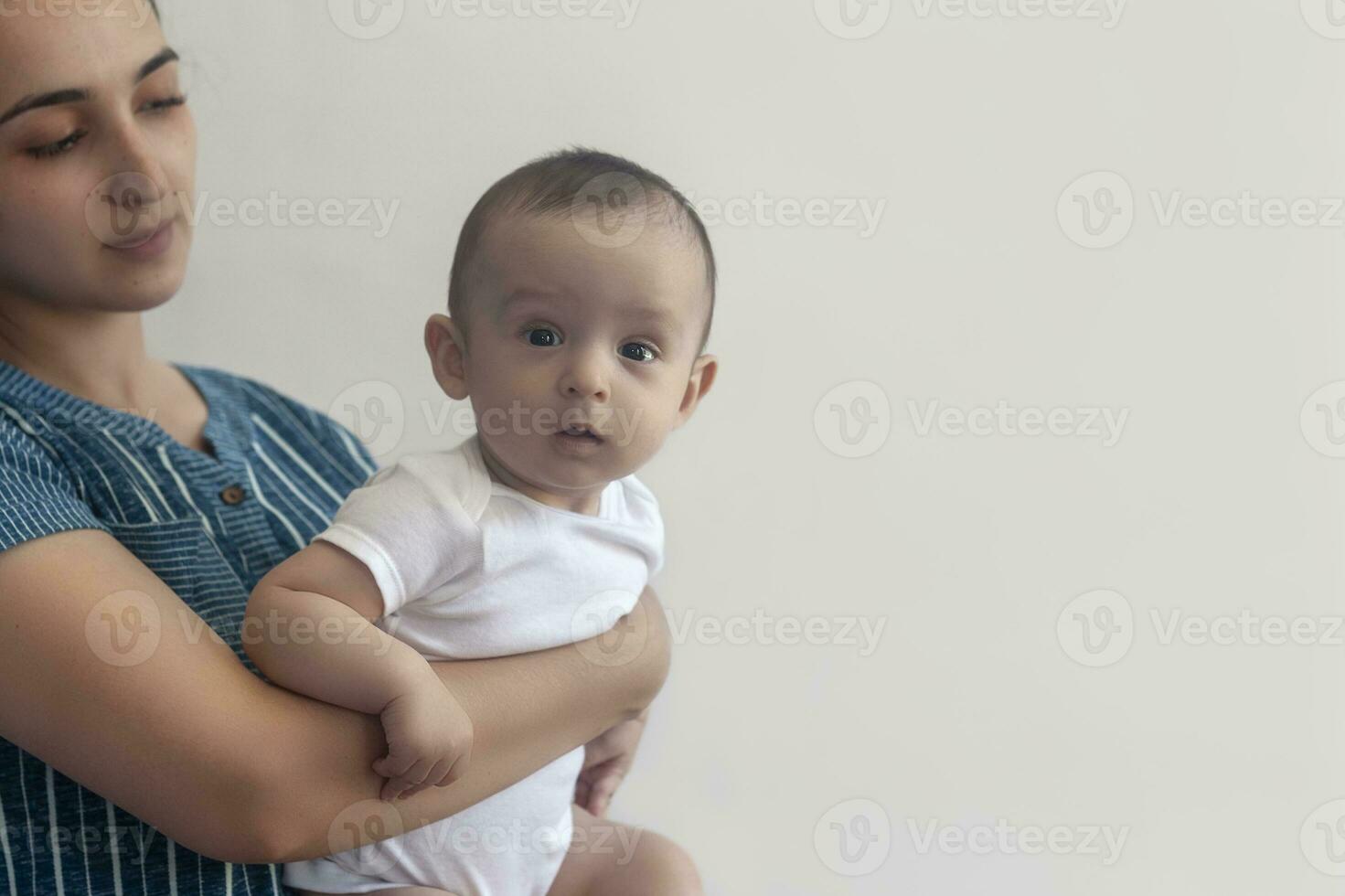 Mutter und Baby. Mama halten ihr 6 Monate Baby Junge. schön Baby Junge von sechs Monate im seine Mutter Hände. jung Mitte östlichen Mutter halten im ihr Waffen ihr wenig Sohn foto