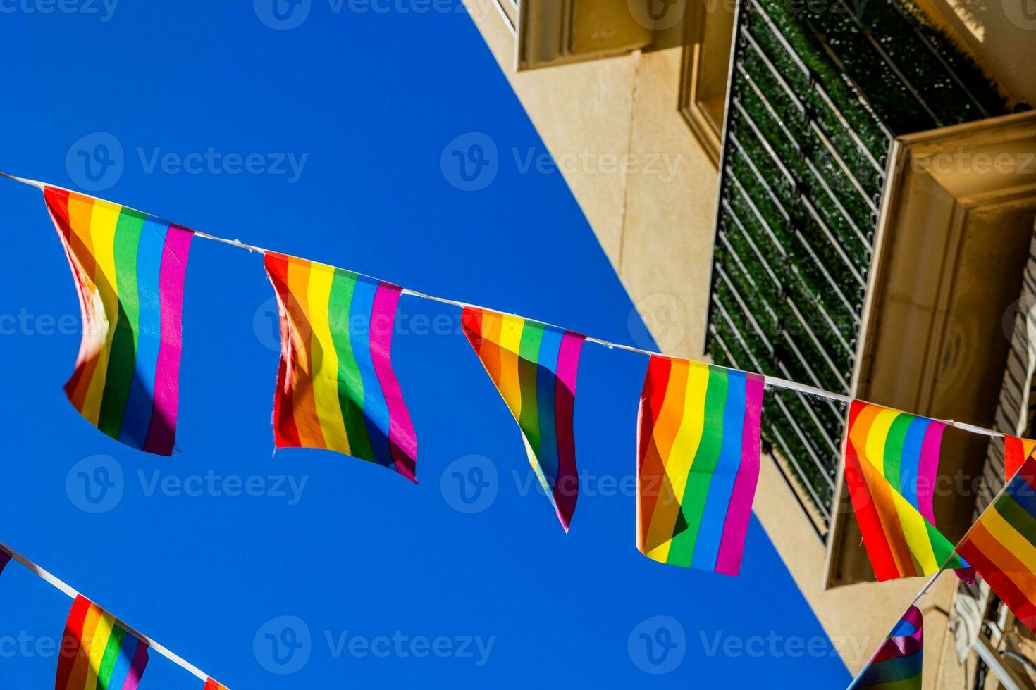 klein Regenbogen Flagge gegen das Himmel im ein Spanisch Stadt foto