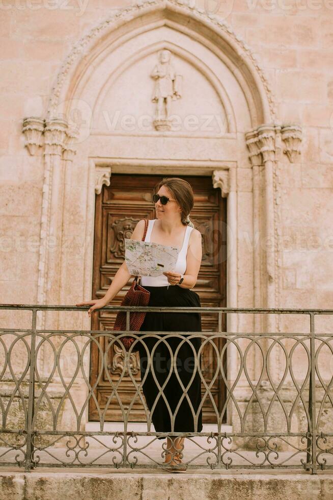 weiblich Tourist mit Stadt Karte durch das Kirche san francesco dassisi im Ostuni, Italien foto