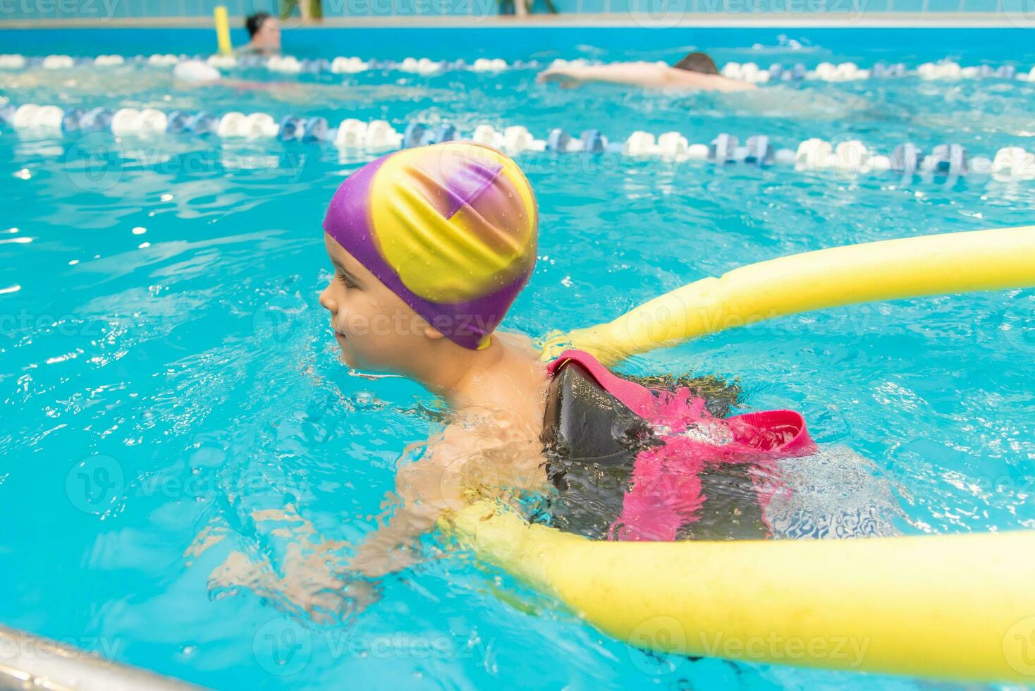 ein wenig Junge mit ein Leben Jacke auf seine Truhe lernt zu schwimmen im ein Innen- Schwimmbad. foto