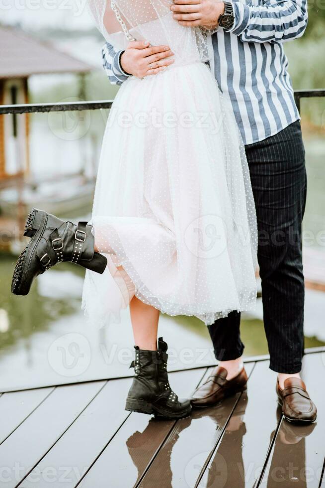 Beine von das Jungvermählten auf das Hintergrund von das pier.the Braut und Bräutigam Stand und Pose im Schuhe auf das Kai. foto