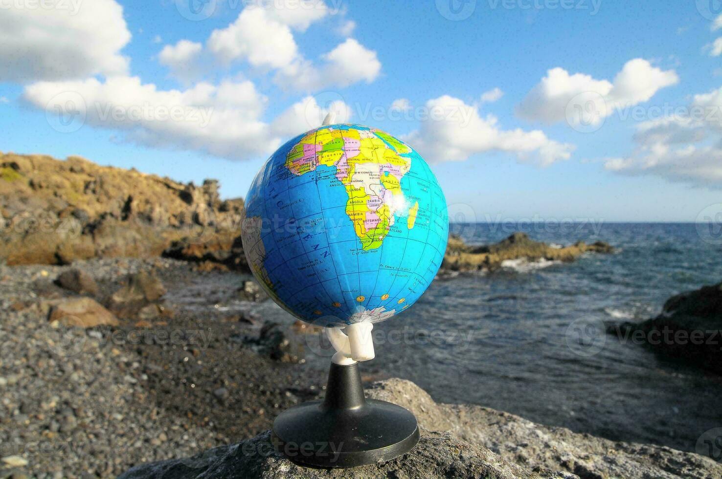 ein Globus auf ein Felsen in der Nähe von das Ozean foto