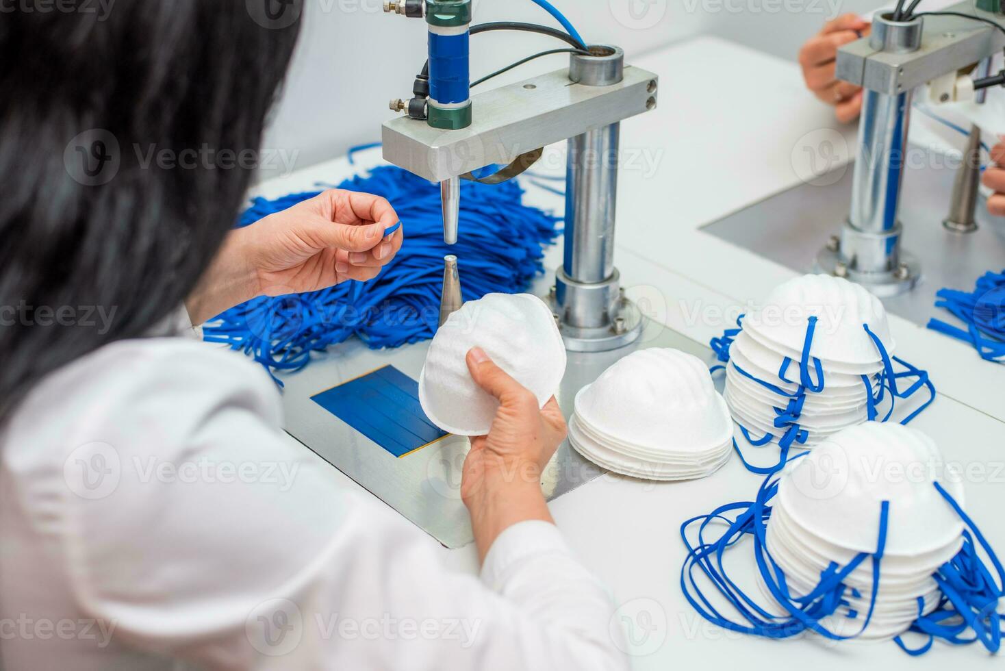 Frauen Arbeit beim ein Maschine zum das Herstellung von medizinisch Masken mit Nanofaser und löten Schleifen zu Sie mit Ultraschall. Coronovirus und covid-19 Verhütung foto