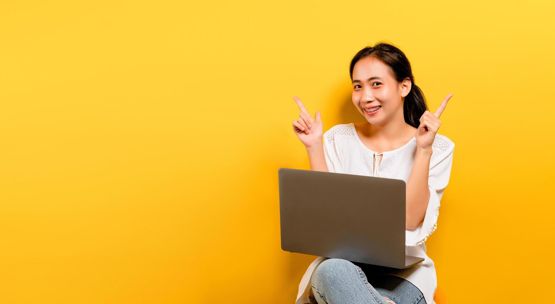 asiatische Frau, die an seinem Laptop arbeitet und ein glückliches Lächeln foto