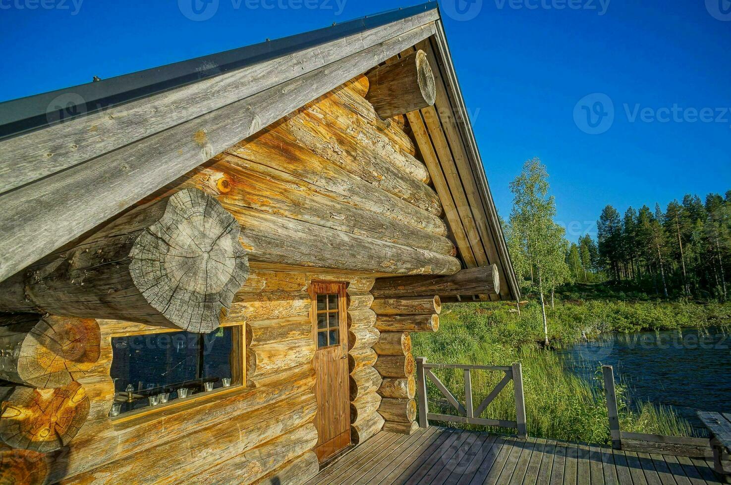 ein Log Kabine mit ein hölzern Deck und ein See im das Hintergrund foto