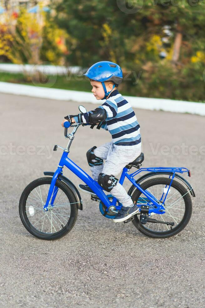 ein Kind im ein Helm und Schutz im ein Fahrrad Reiten auf Natur im das Frühling foto