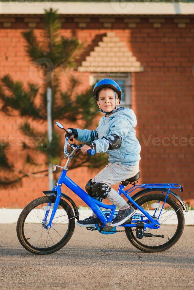 wenig Junge im Helm Fahrten ein Fahrrad auf ein sonnig Tag foto