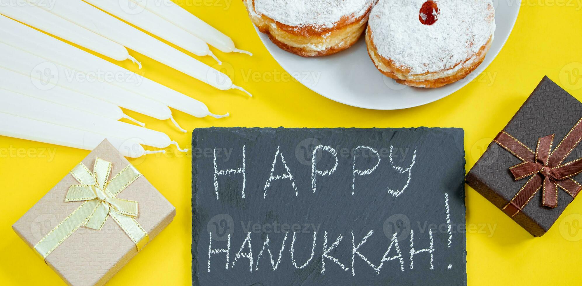 Fröhliches Hanukkah. jüdisches dessert sufganiyot auf gelbem hintergrund. symbole des religiösen judentums. Donuts, Kerzen und Geschenk. foto