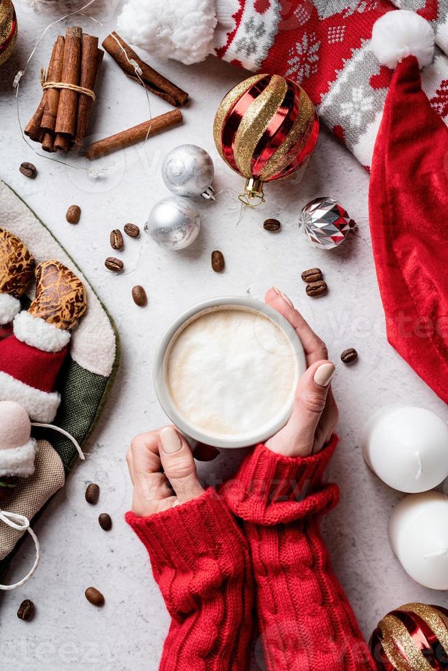 Weihnachtsdesktop mit Frauenhänden, die eine Tasse Kaffee halten foto