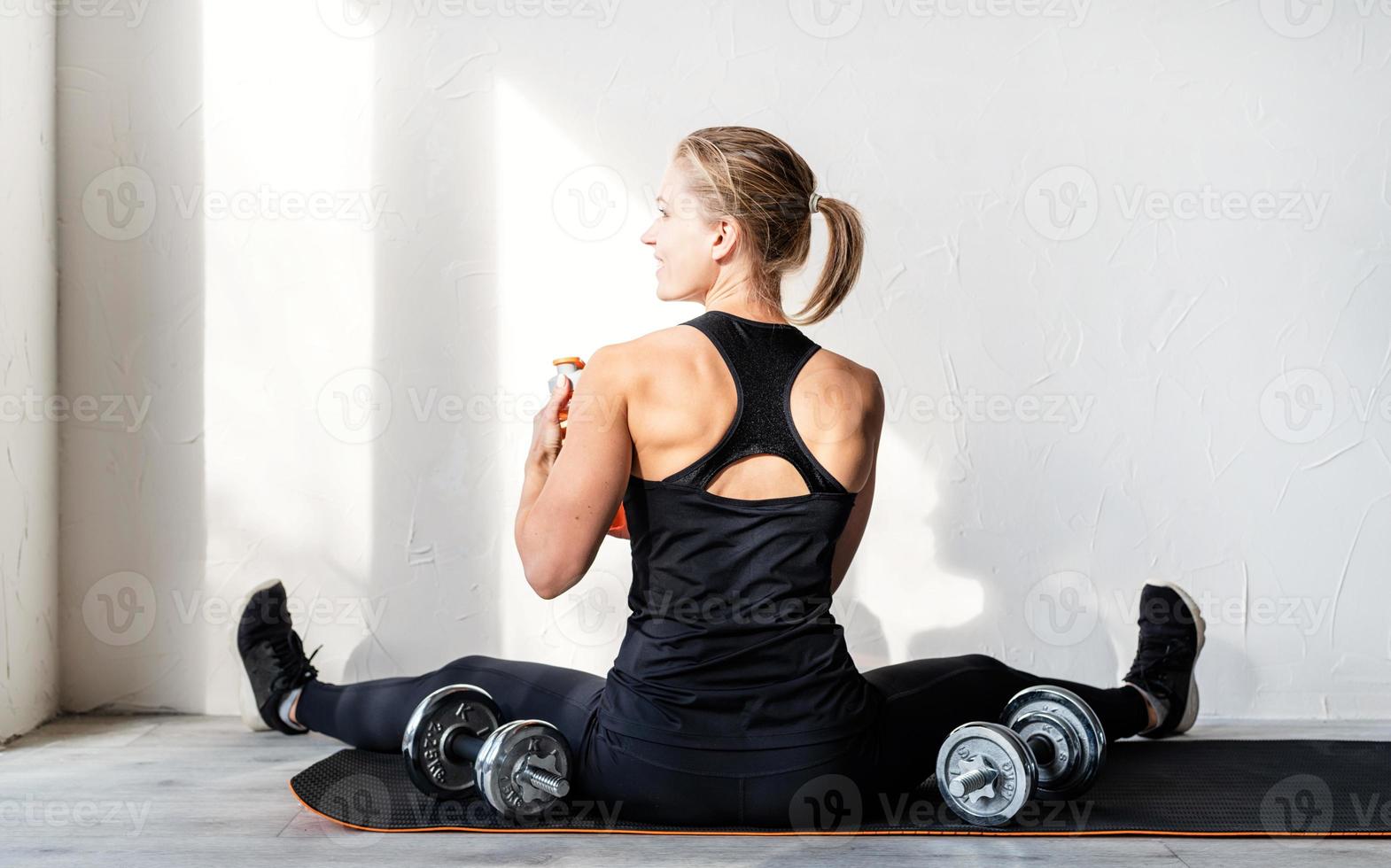 Frau, die mit Hanteln trainiert und ihre Rücken- und Armmuskulatur zeigt foto