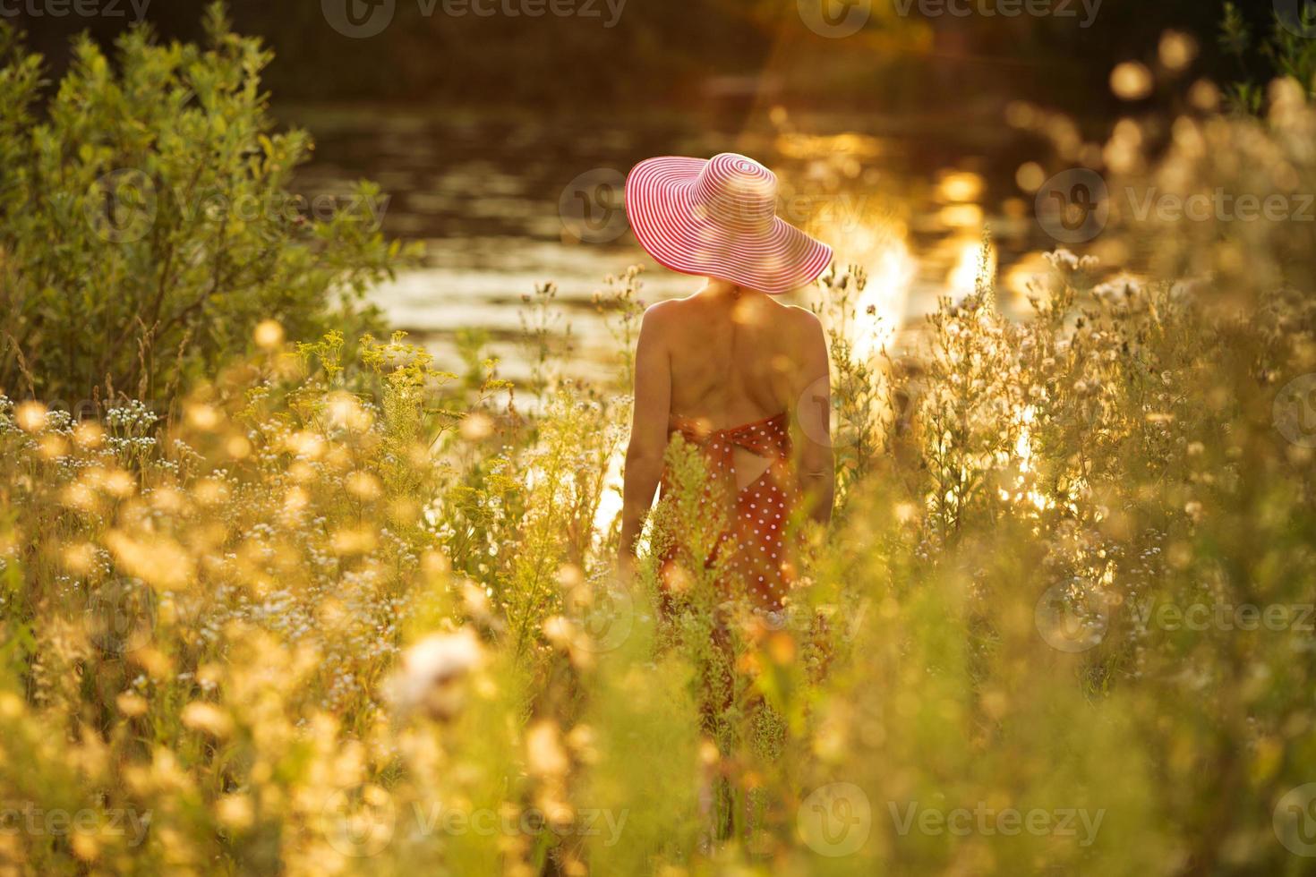 Frau mit Hut an einem Sommerabend am Wasser foto