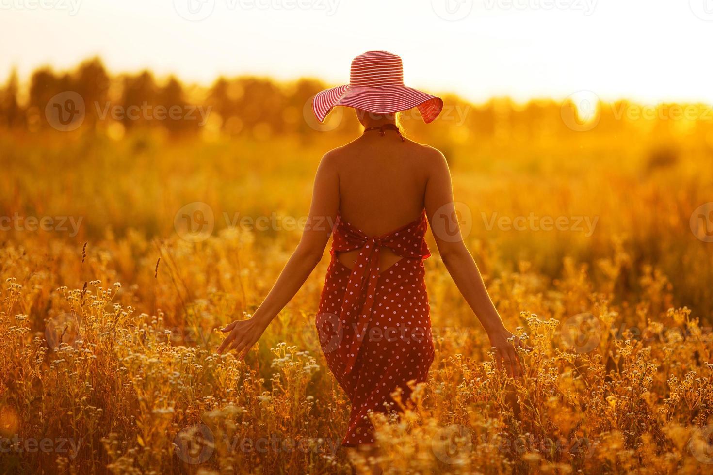 Frau mit Hut geht durch Blumenfelder foto
