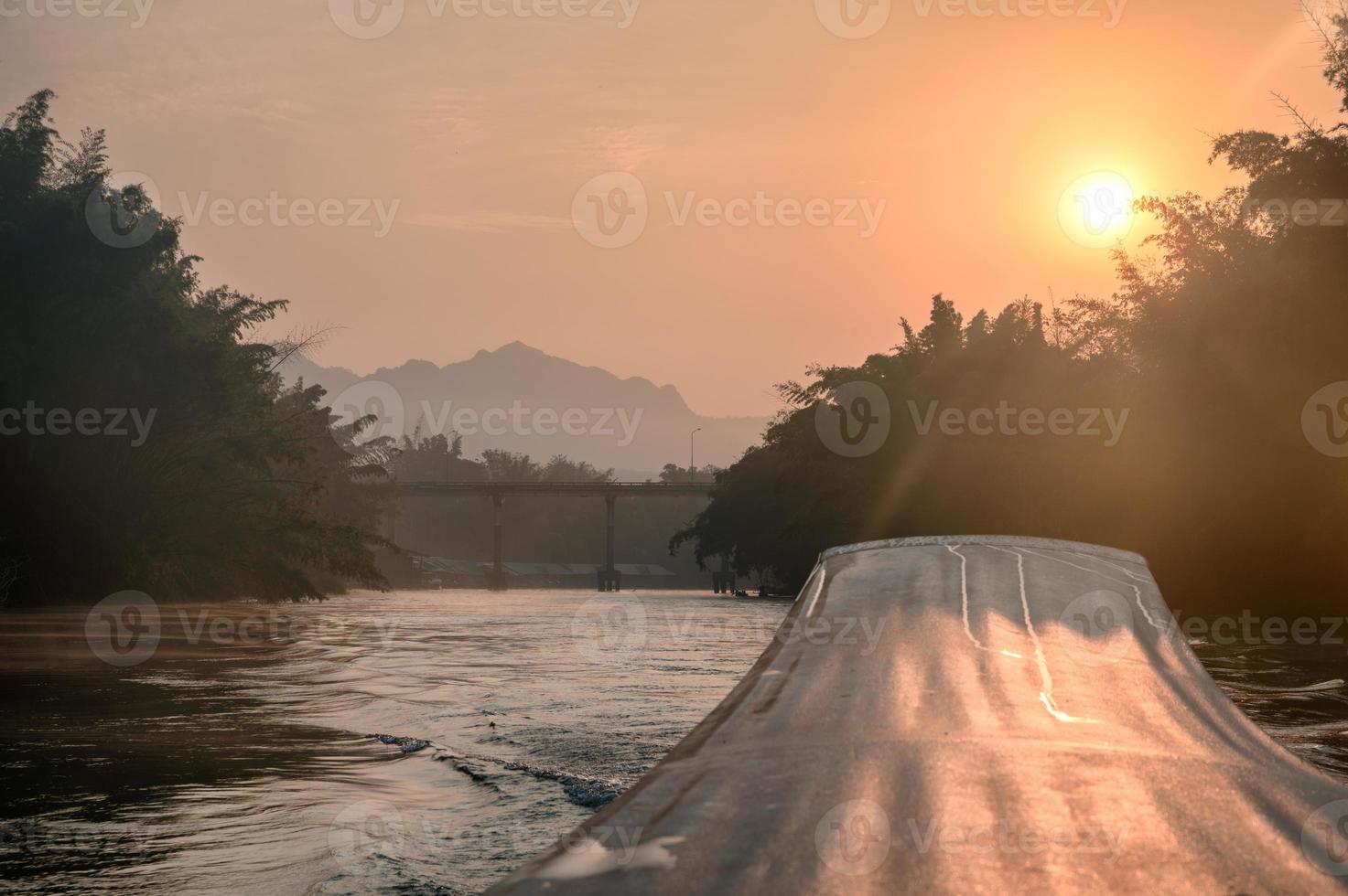 Longtail-Segelboot mit Sonnenaufgang auf der Brücke im Fluss Kwai foto