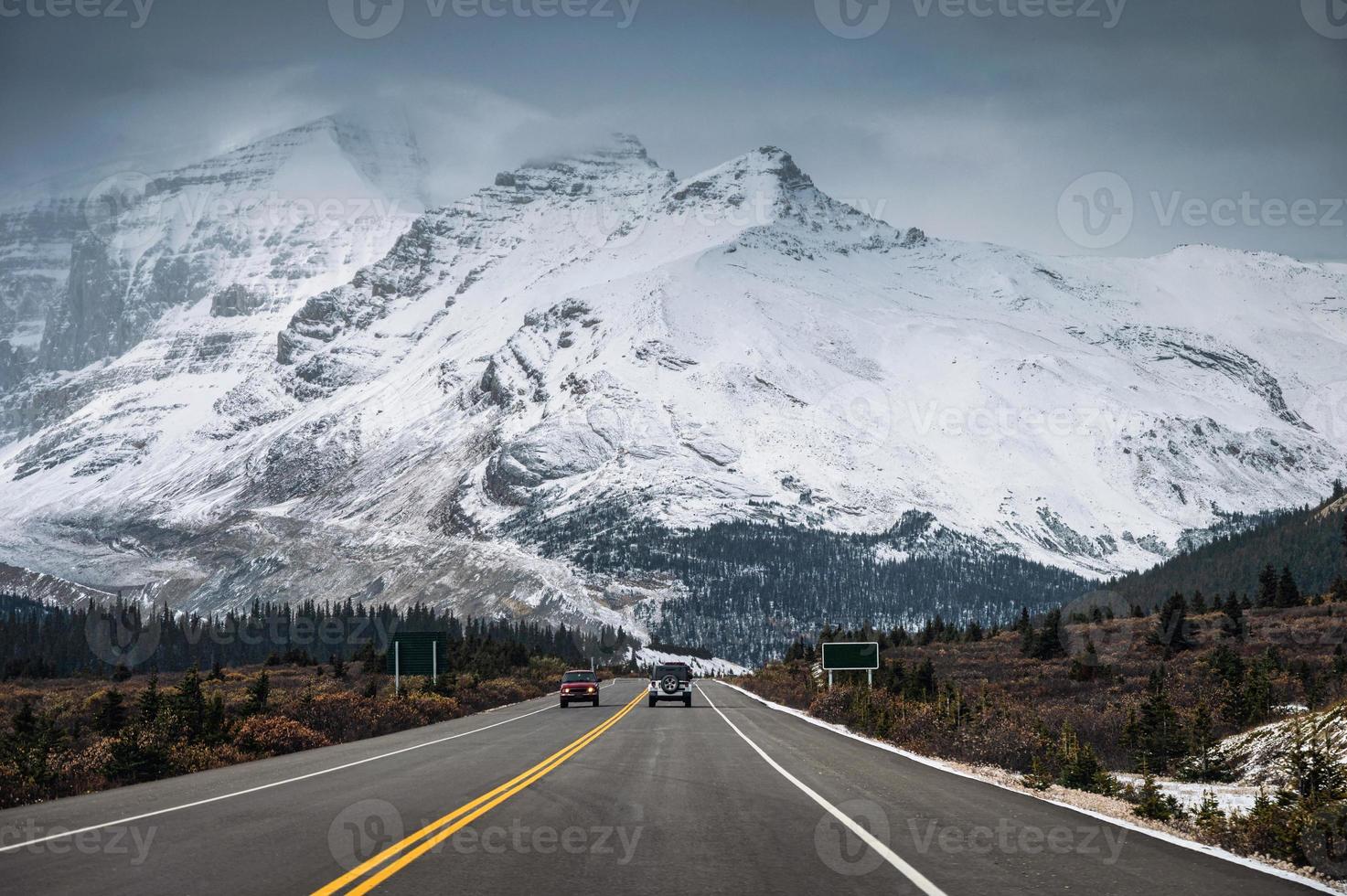 Auto auf Autobahn und schneebedeckter Bergkette im düsteren Icefields Parkway foto
