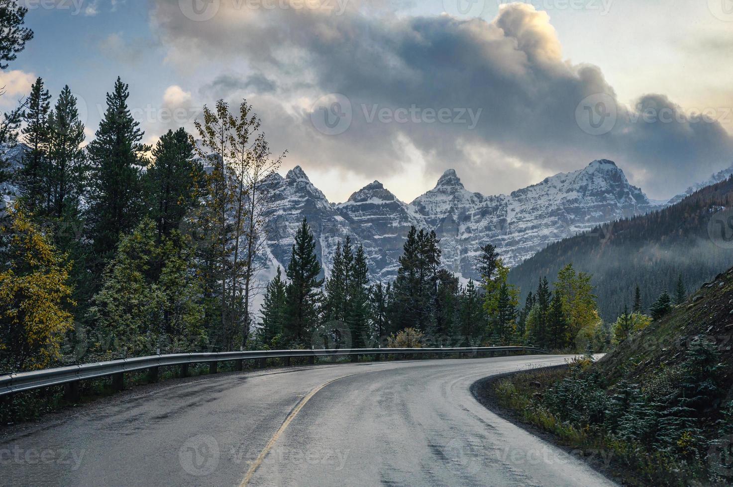 Autobahnstraße mit felsigen Bergen im Kiefernwald am Moränensee im Banff-Nationalpark foto