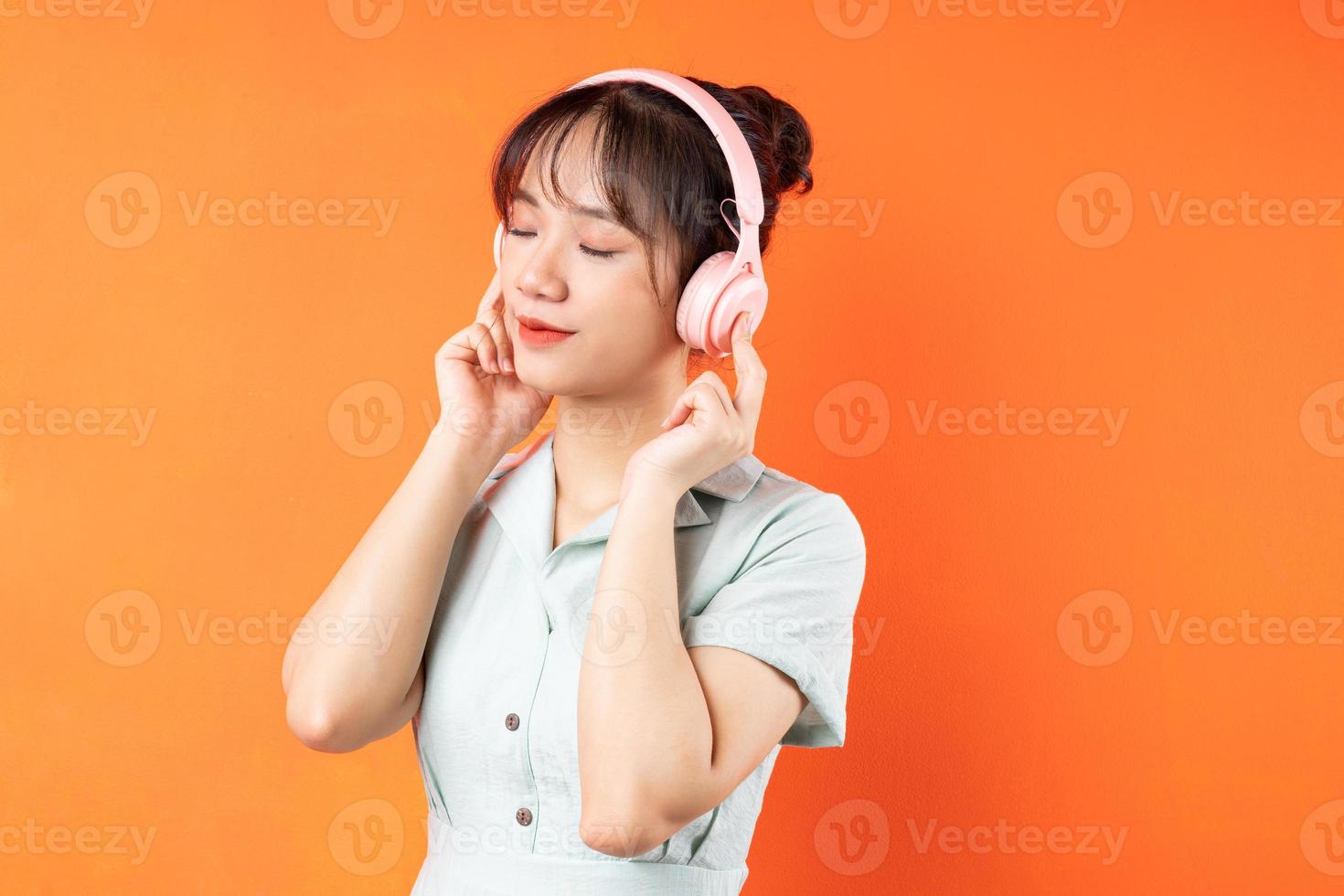 Porträt eines jungen Mädchens, das Musik hört und sich entspannt, isoliert auf orangefarbenem Hintergrund foto