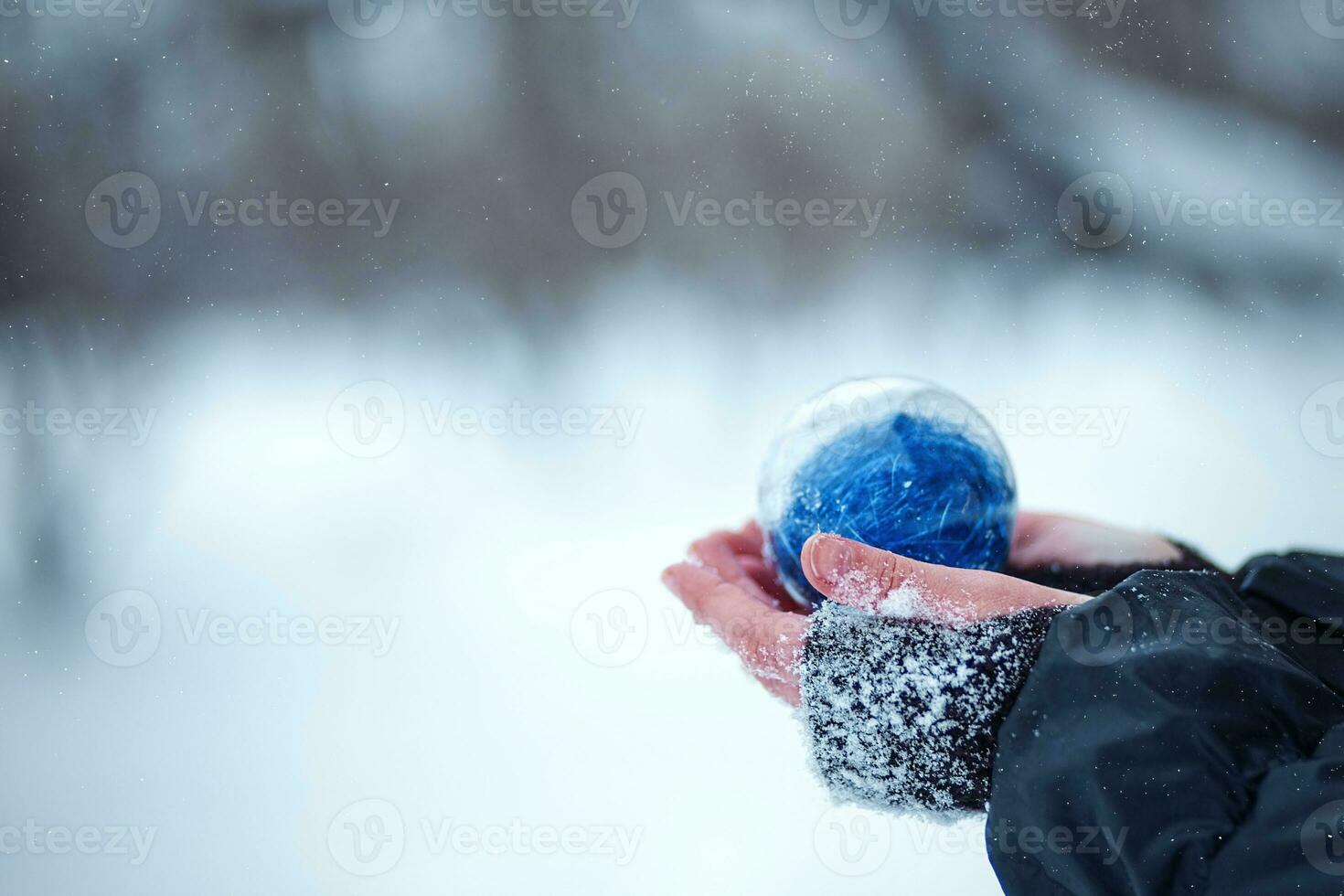 Weihnachten Baum Spielzeug im das Hände von ein Kind. runden Blau Weihnachten Ball auf Schnee Hintergrund. foto