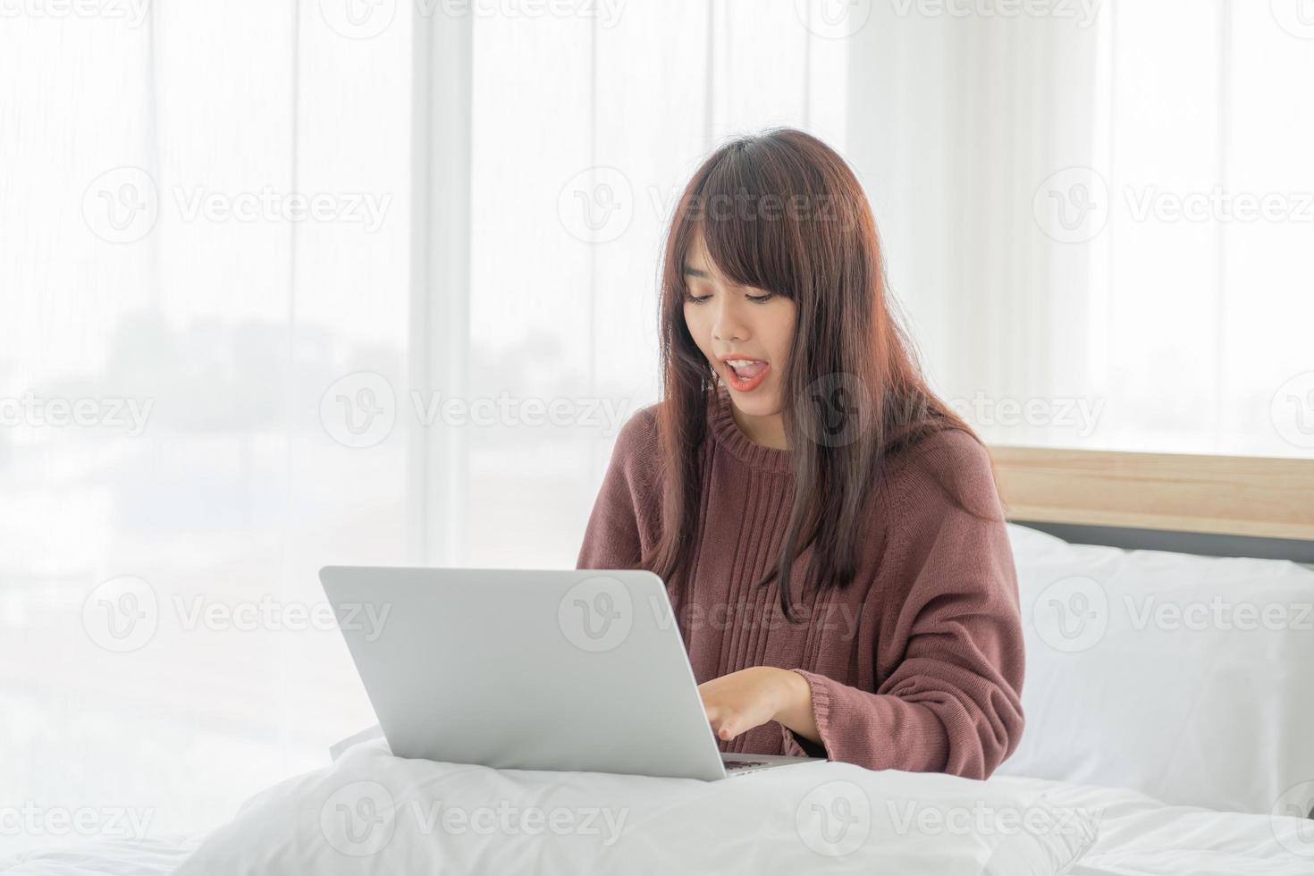 asiatische Frauen, die mit Laptop auf dem Bett arbeiten foto