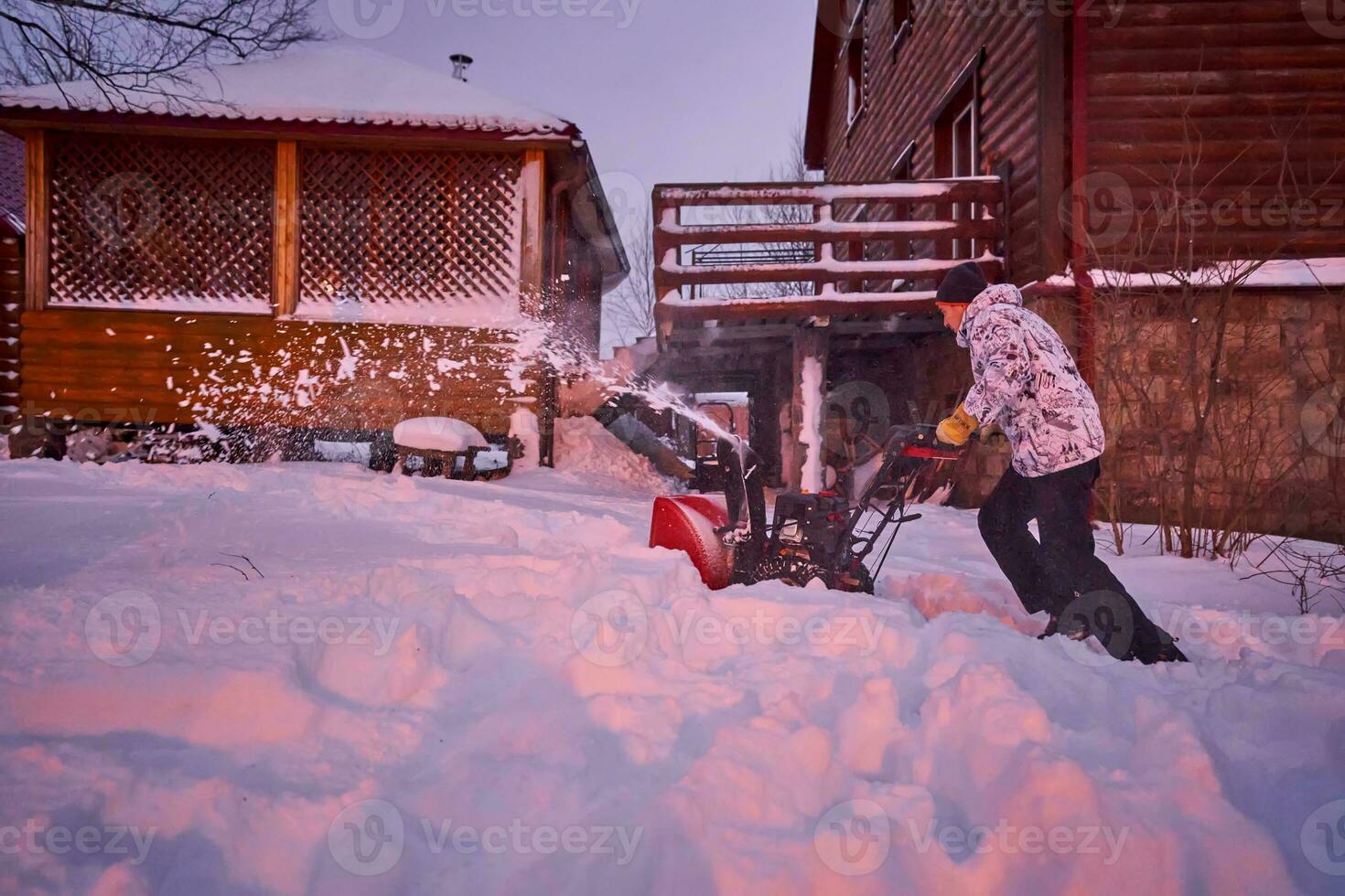 ein jung Mann löscht Schnee mit ein Schnee Gebläse im seine Hof. foto