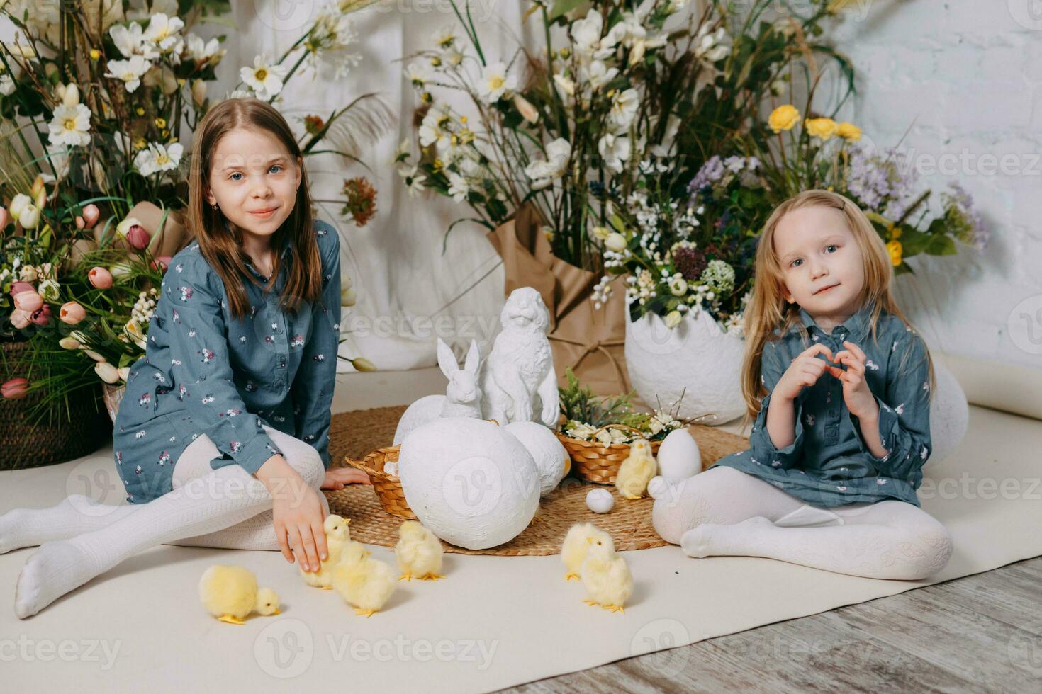 zwei Mädchen im ein schön Ostern Foto Zone mit Blumen, Eier, Hühner und Ostern Hasen. glücklich Ostern Urlaub.