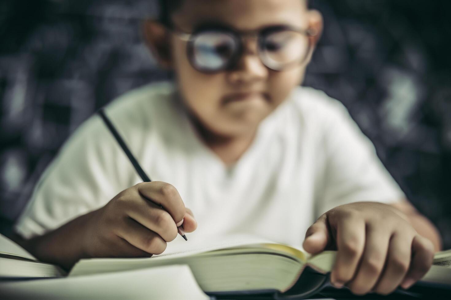 ein Junge mit Brille Mann schreibt im Klassenzimmer foto