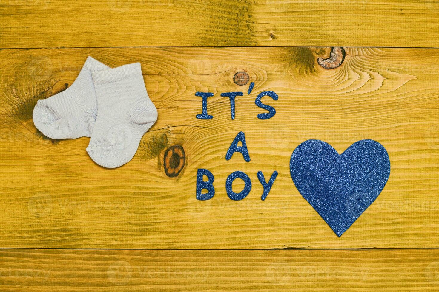 Text es ist ein Junge mit wenig Baby Socken und Herz gestalten auf hölzern Tabelle foto