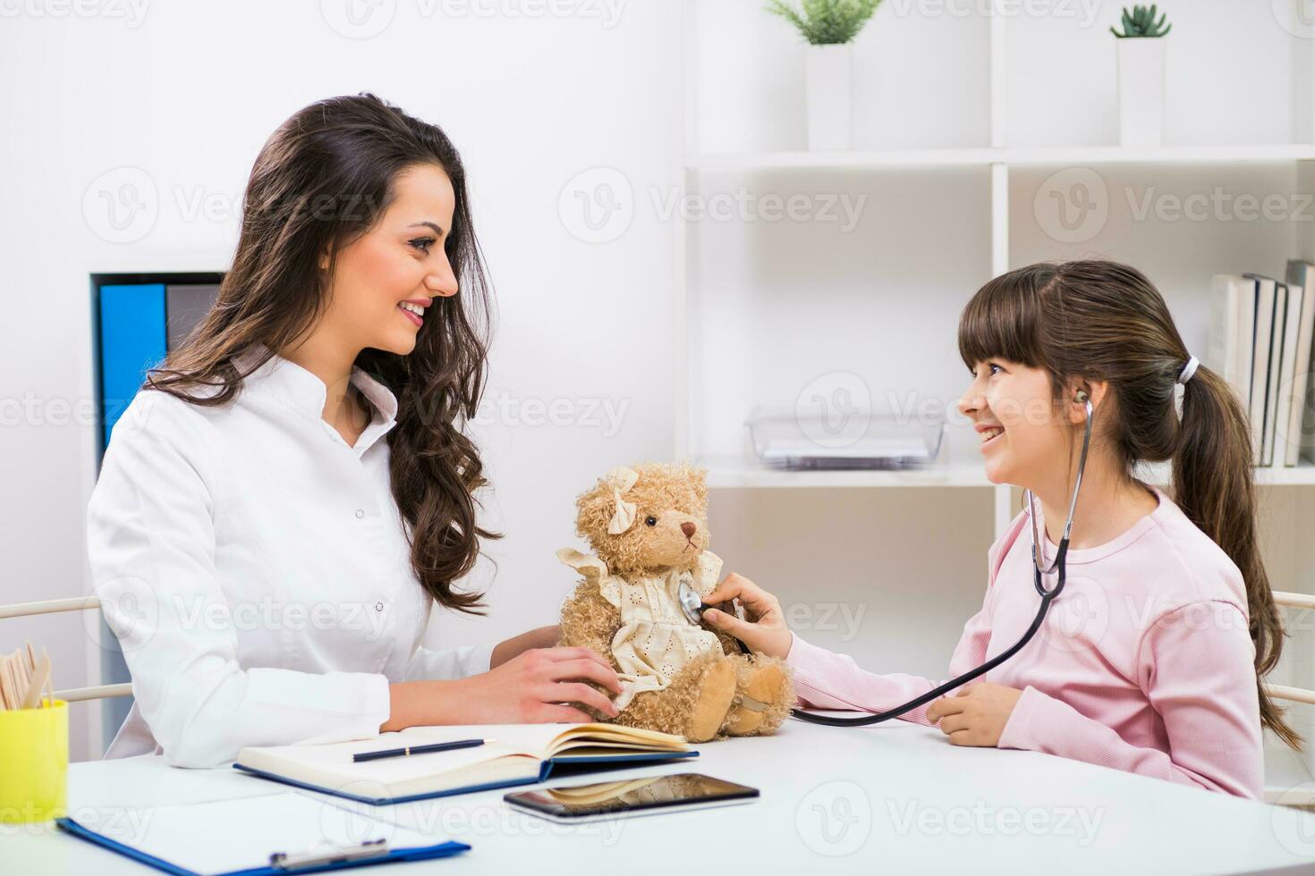 weiblich Arzt und wenig Mädchen Prüfung Teddy Bär beim medizinisch Büro foto