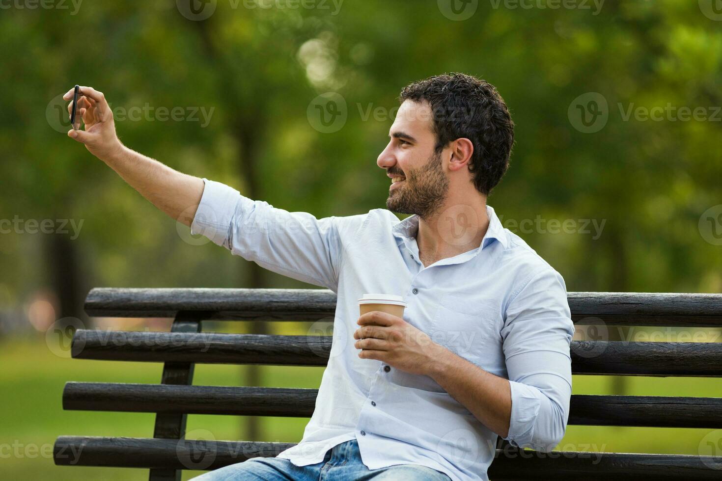 jung Geschäftsmann ist ruhen beim das parken, nehmen Selfie und Trinken Kaffee foto