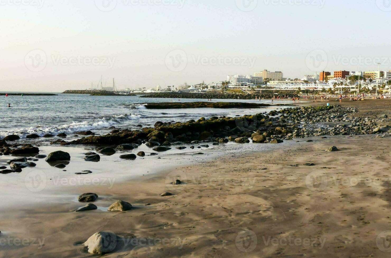 ein Strand mit Felsen und Sand im Vorderseite von das Ozean foto