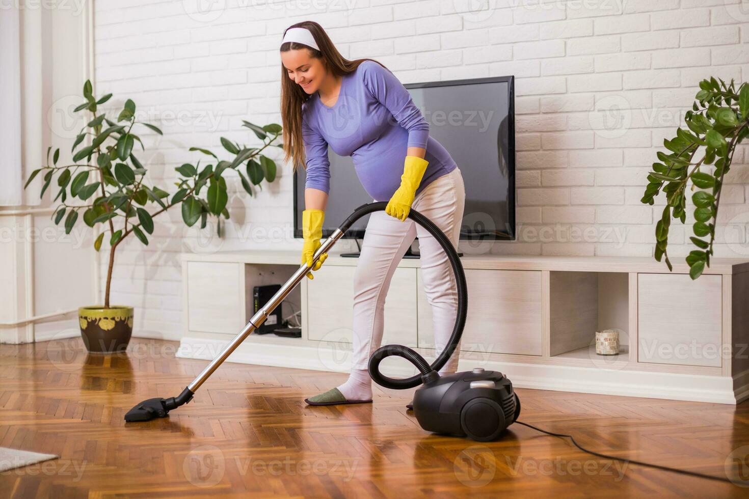schön schwanger Frau genießt Reinigung ihr Haus. foto