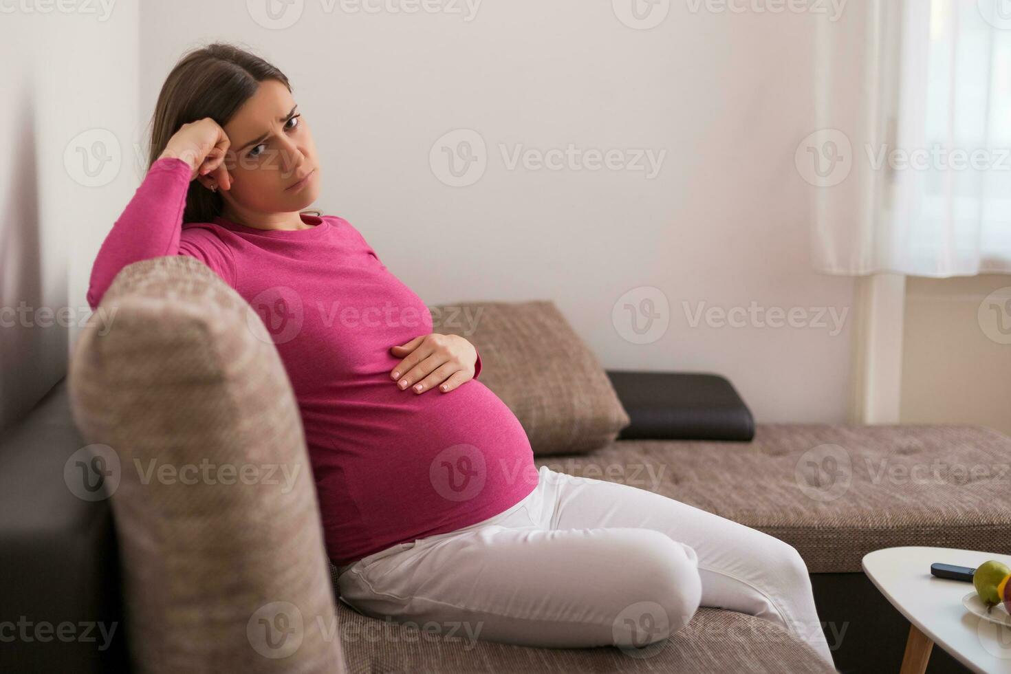 traurig schwanger Frau müde von Schwangerschaft ist Sitzung auf Sofa beim ihr heim. foto