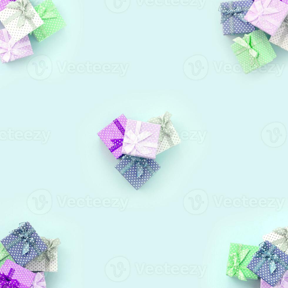 Stapel von kleinen farbigen Geschenkboxen mit Bändern liegen auf violettem Hintergrund. Minimalismus flaches Draufsichtmuster foto